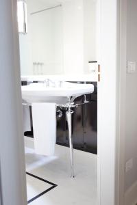 a white bathroom with a sink and a mirror at Hotel Riviera & Maximilian's in Trieste