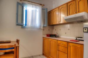 uma pequena cozinha com armários de madeira e uma janela em Kalithea Studios em Patitiri