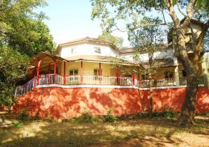 a yellow house with a porch and a tree at Westend Hotel in Matheran