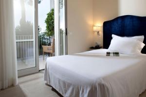 a bedroom with a large white bed and a balcony at Hotel Riviera & Maximilian's in Trieste