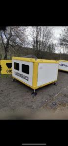 un remolque blanco y amarillo sentado en un estacionamiento en BCC Lochness Glamping, en Bearnock