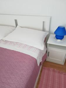 Apartman Legac في ستاريغراد: سرير أبيض مع مزهرية زرقاء على موقف ليلي