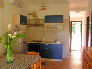 a kitchen with a table with a vase of flowers at Villetta Tekios in Villasimius