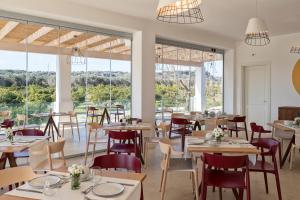 ein Restaurant mit Tischen und Stühlen und großen Fenstern in der Unterkunft Palummare - Agri Hotel Relais in Torre San Giovanni Ugento