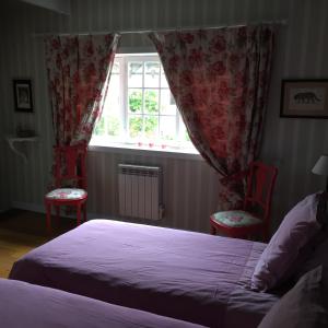 een slaapkamer met een bed en 2 stoelen en een raam bij Chambres d'hôtes L'Aubaine avec jacuzzi in Wanquetin