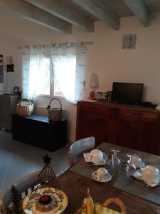 a living room with a table and a television at Aux Cadollines in Romenay