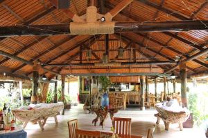 Habitación con mesas, sillas y techo de madera. en Hotel Chateau St Cloud, en La Digue