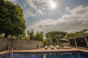 a swimming pool with chairs and a stone wall at Gateway Hotel in Port Moresby