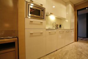 a kitchen with white cabinets and a microwave at Si Lin Apartment in Guangzhou