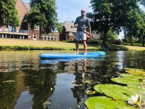 a man standing on a paddle board in the water at Canal House - Homestay in Alkmaar