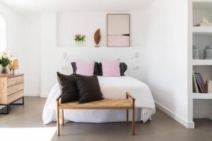 a bedroom with a white bed with pink and black pillows at Las Flores de Marta (Milla de Oro - Marbella) in Marbella