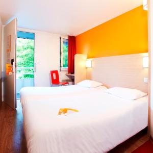 a hotel room with two beds and a red chair at Premiere Classe Lille Sud - Douai Cuincy in Cuincy