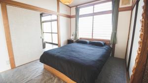 a bedroom with a bed in a room with windows at Furano View House in Furano