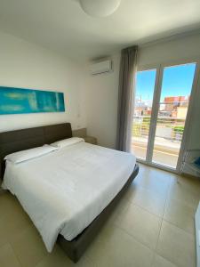 1 dormitorio con cama grande y ventana grande en Vespucci Apartments Torre Lapillo, en Torre Lapillo