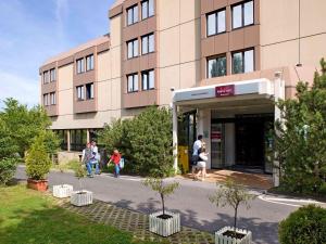 personnes marchant à l'extérieur d'un bâtiment avec des arbres devant dans l'établissement Mercure Bonn Hardtberg, à Bonn