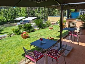 un patio con due tavoli e sedie sotto un ombrellone di Il Casale nel Parco Guesthouse a Roma