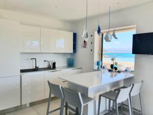a kitchen with white cabinets and a table with chairs at Appartamento delfino azzurro in Golfo Aranci