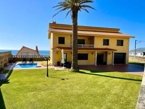 a yellow house with a palm tree and a yard at Casa Con Piscina Junto Al Mar in Oia