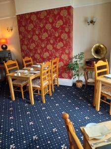 ein Esszimmer mit Tischen und Stühlen und einer roten Wand in der Unterkunft Beach Cove in Llandudno