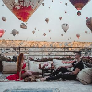 a couple sitting on a couch with hot air balloons at Artemis Cave Suites & Spa- Adults Only in Göreme