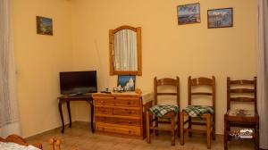 a room with a desk with a television and two chairs at Eirini Kasimiotou Apartments in Agios Andreas
