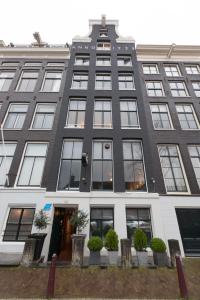 een groot zwart-wit gebouw met ramen bij Hotel Hermitage Amsterdam in Amsterdam