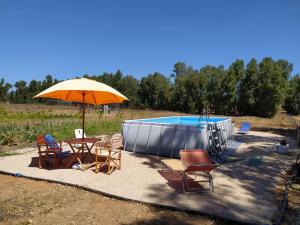 um pátio com cadeiras, um guarda-sol e uma piscina em Bed & Breakfast Pintadera em Santa Maria la Palma