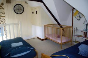 a room with a crib and a clock on the wall at Gîte Charbonnerie in Moncontour