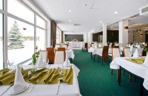 een restaurant met witte tafels en stoelen en grote ramen bij Hotel Wodnik in Slok