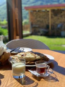 a table with a plate of food and two glasses of milk at Albanian traditional Villa in Librazhd