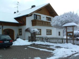 una casa cubierta de nieve con un coche aparcado delante de ella en Landhaus Petra, en Bad Füssing