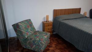 um quarto com uma cama e uma cadeira ao lado de uma cama em Quartos Cesário Verde Massamá em Queluz