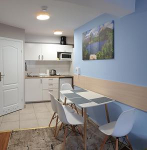 a kitchen with a table and chairs in a room at Pałac Tatrzański Apartament Tatry in Bukowina Tatrzańska