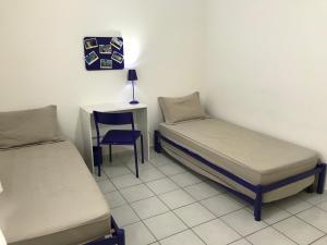 a room with two beds and a table and a chair at Apartamento Confortavel em Balneário Camboriu in Balneário Camboriú
