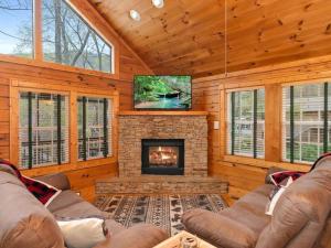a living room with a fireplace and a tv at Soco Serene Cabin in the Heart of Maggie Valley in Maggie Valley