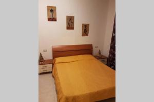 a bedroom with a bed with a yellow blanket at Palma BnB in Maracalagonis