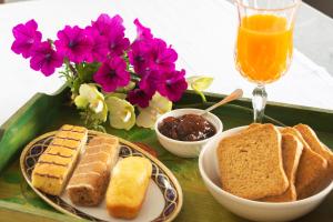 a tray with bread and a glass of orange juice and flowers at Villetta Belvedere in Piacenza