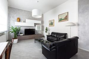 sala de estar con sofá de cuero negro y TV en Villetta Belvedere, en Piacenza