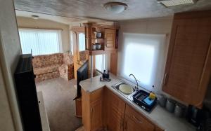 a small kitchen with a sink and a living room at Staycation Opposite Fantasy Island Ingoldmells in Ingoldmells