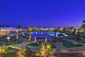 a pool at night with umbrellas and palm trees at Coral Beach Resort Montazah (Ex. Rotana) in Sharm El Sheikh