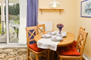 a dining room table and chairs with a table and flowers at Fewo Kliff 46, EG in Ostseebad Nienhagen