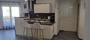 una cocina con 2 taburetes y una barra en IKON apartman, en Hajdúszoboszló