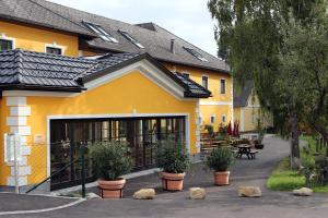 un bâtiment jaune avec des plantes devant lui dans l'établissement Perbersdorfer Heuriger, à Neuhofen an der Ybbs