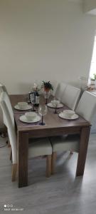 una mesa de madera con platos y copas de vino. en Apartament w spokojnej lokalizacji en Cieplewo