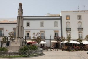 a large white building with a monument in front of it at Tavira Home in Tavira