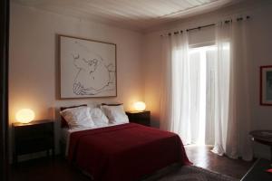a bedroom with a bed with a red blanket and a window at Tavira Home in Tavira
