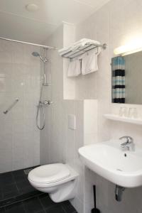 a white bathroom with a toilet and a sink at Hotel de Burg in Domburg