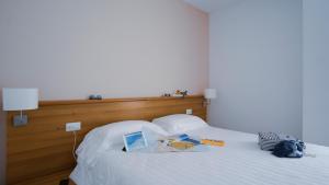 オリスターノにあるMistral2 Hotelの白いベッド(上に本付)