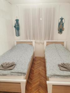 two beds in a small room with wooden floors at Kuća Zlatica in Palić
