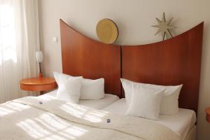 ein Bett mit weißen Kissen und einem Kopfteil aus Holz in der Unterkunft Palais Schrottenberg in Bamberg
